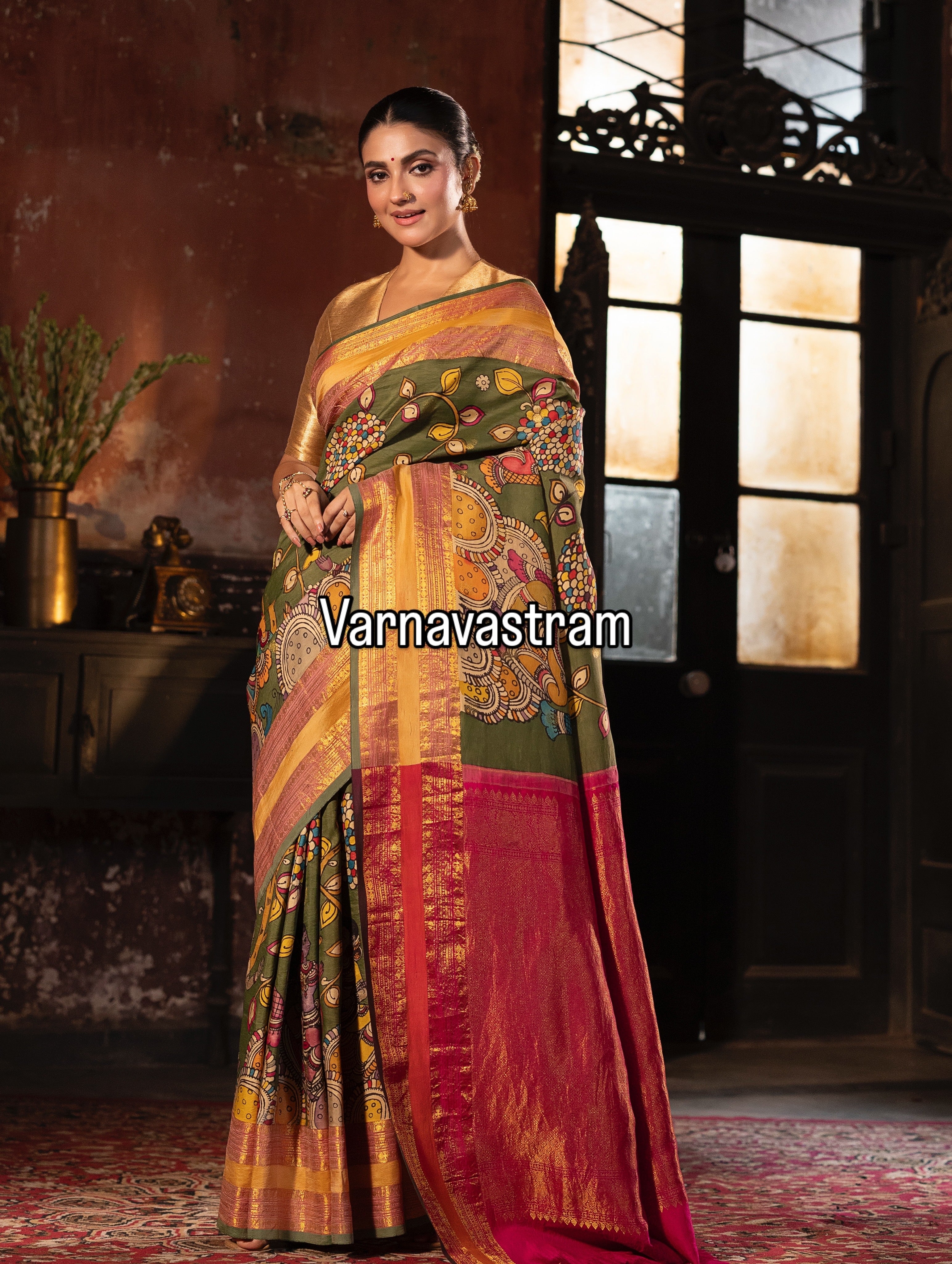A beautiful and traditional korvai kanchivaram silk saree adorned with forest green base , dancing apsaras and floral creepers Handdrawn handpainted penkalamkari