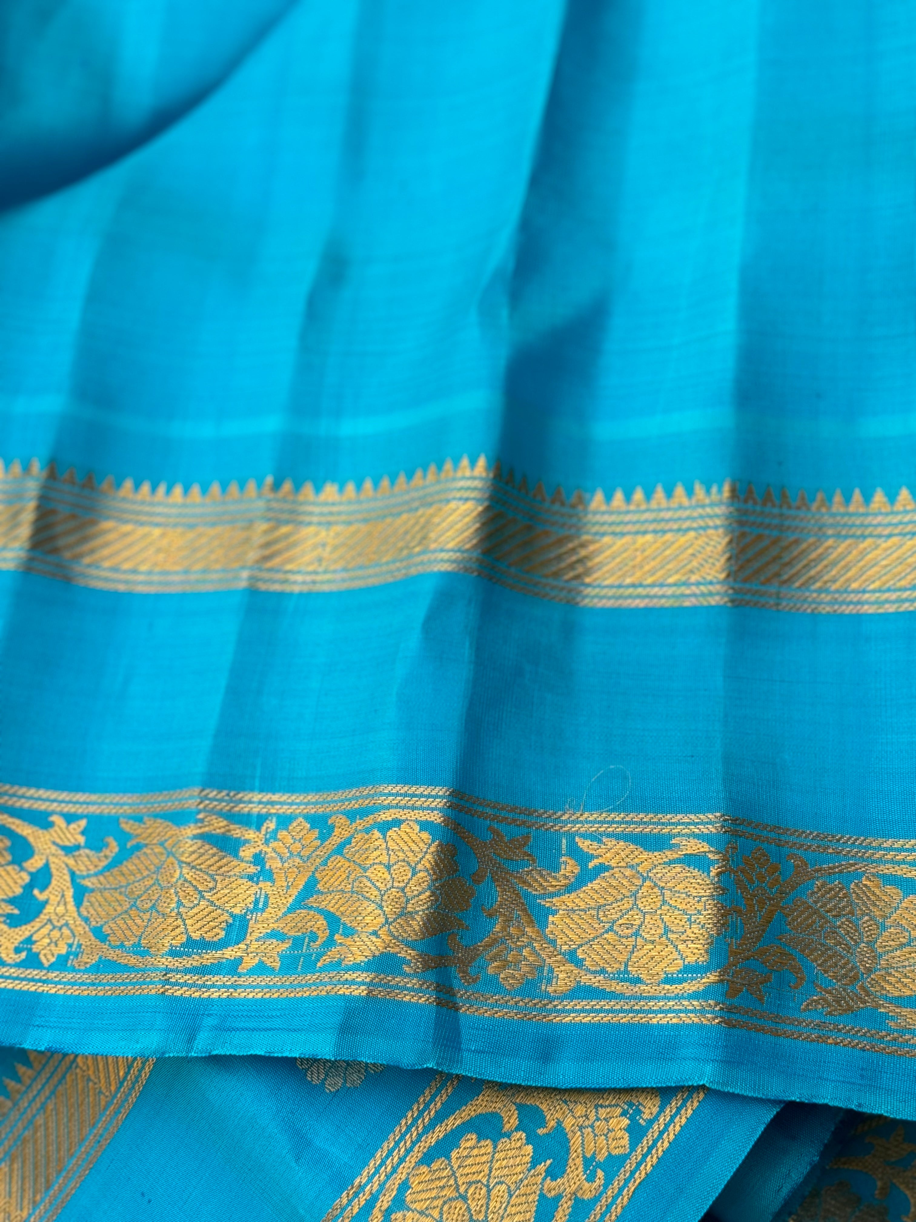 An Elegant sunset Orange with blue Gadwal silk saree with meenakari border