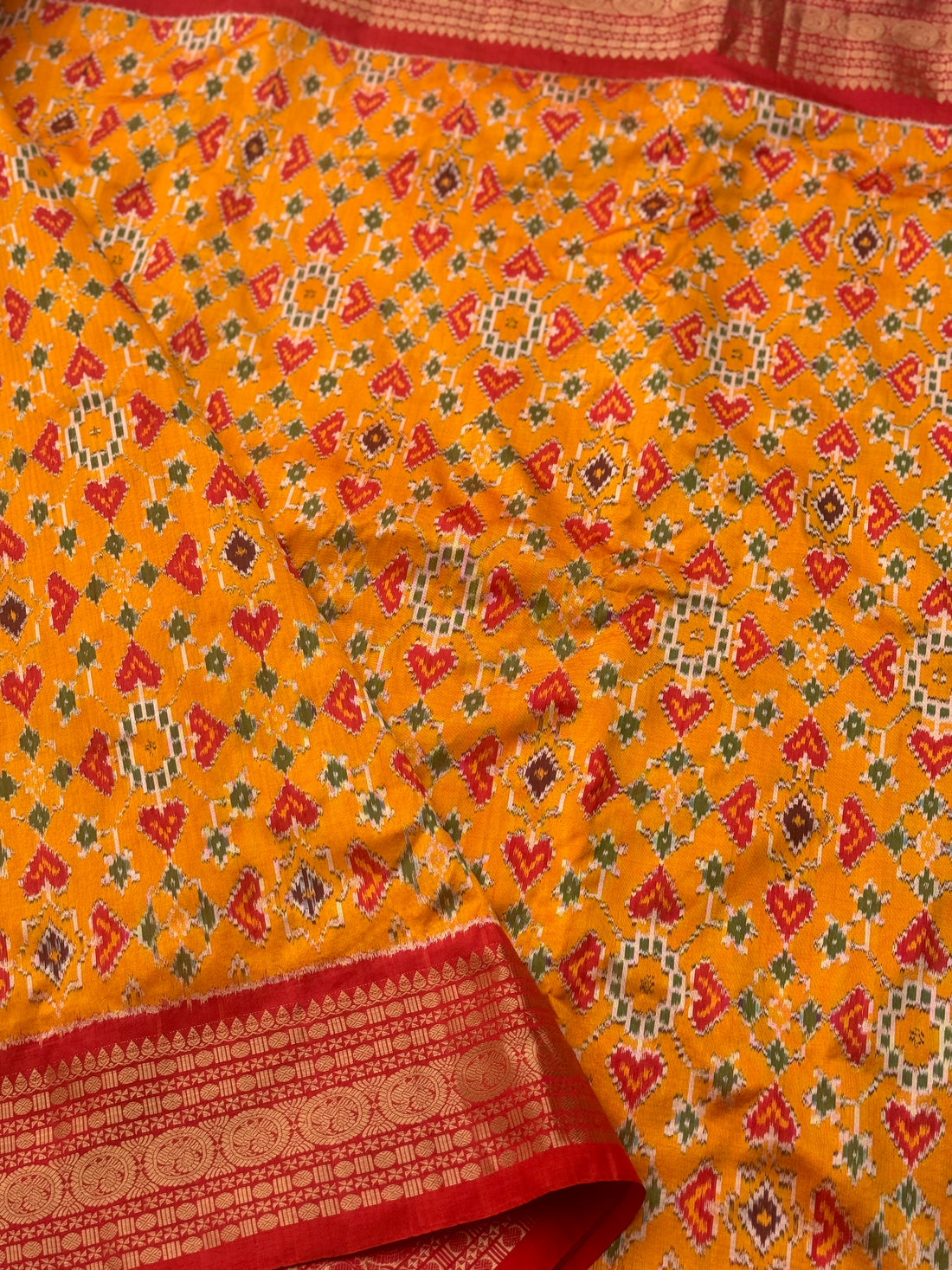 Yellowish orange with red kanchi jacquard weave zari border patola inspired navratan ikkat design on pure mulberry silk fabric