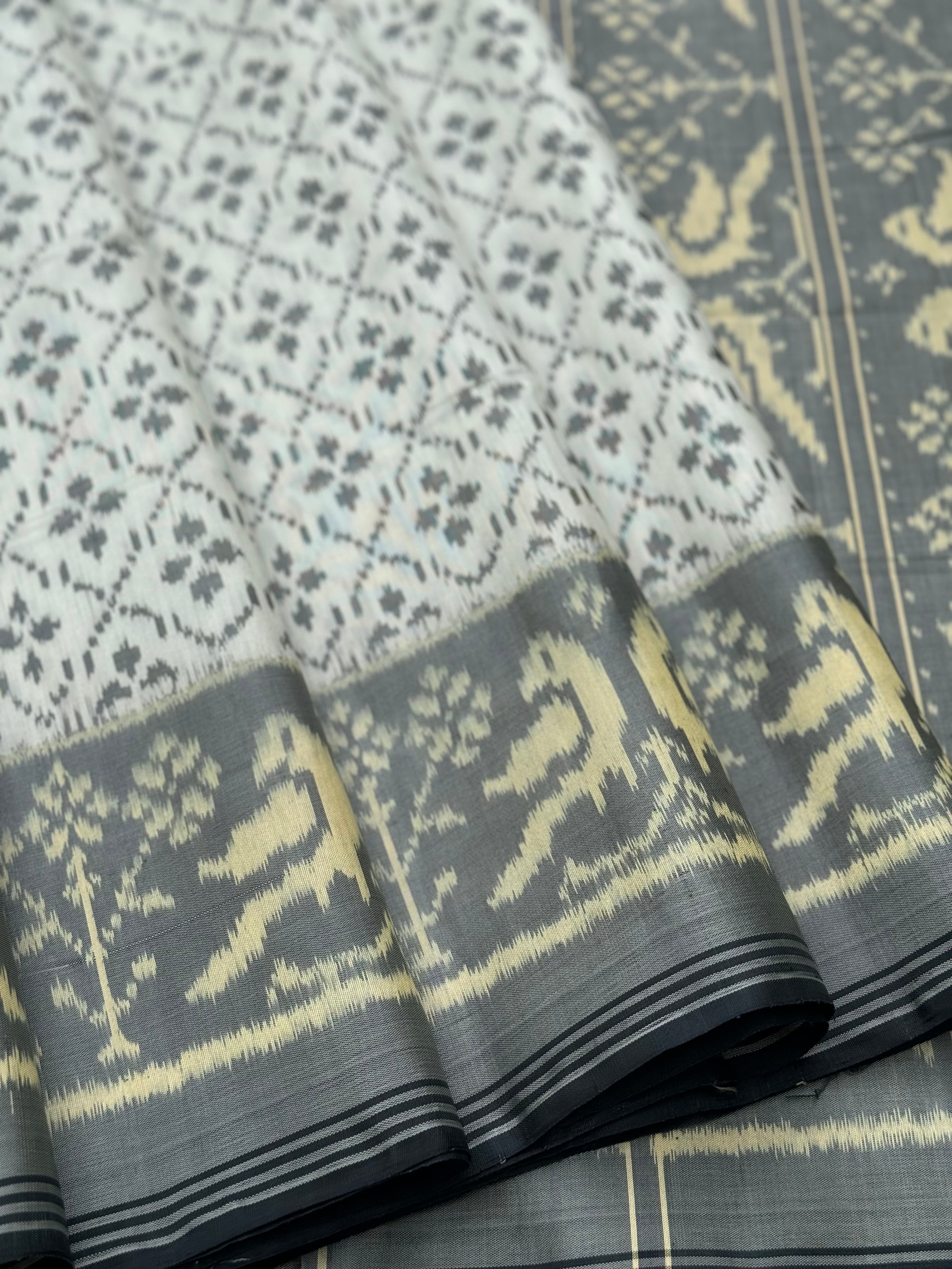 A gorgeous pearl white with grey single ikkat patola silk saree