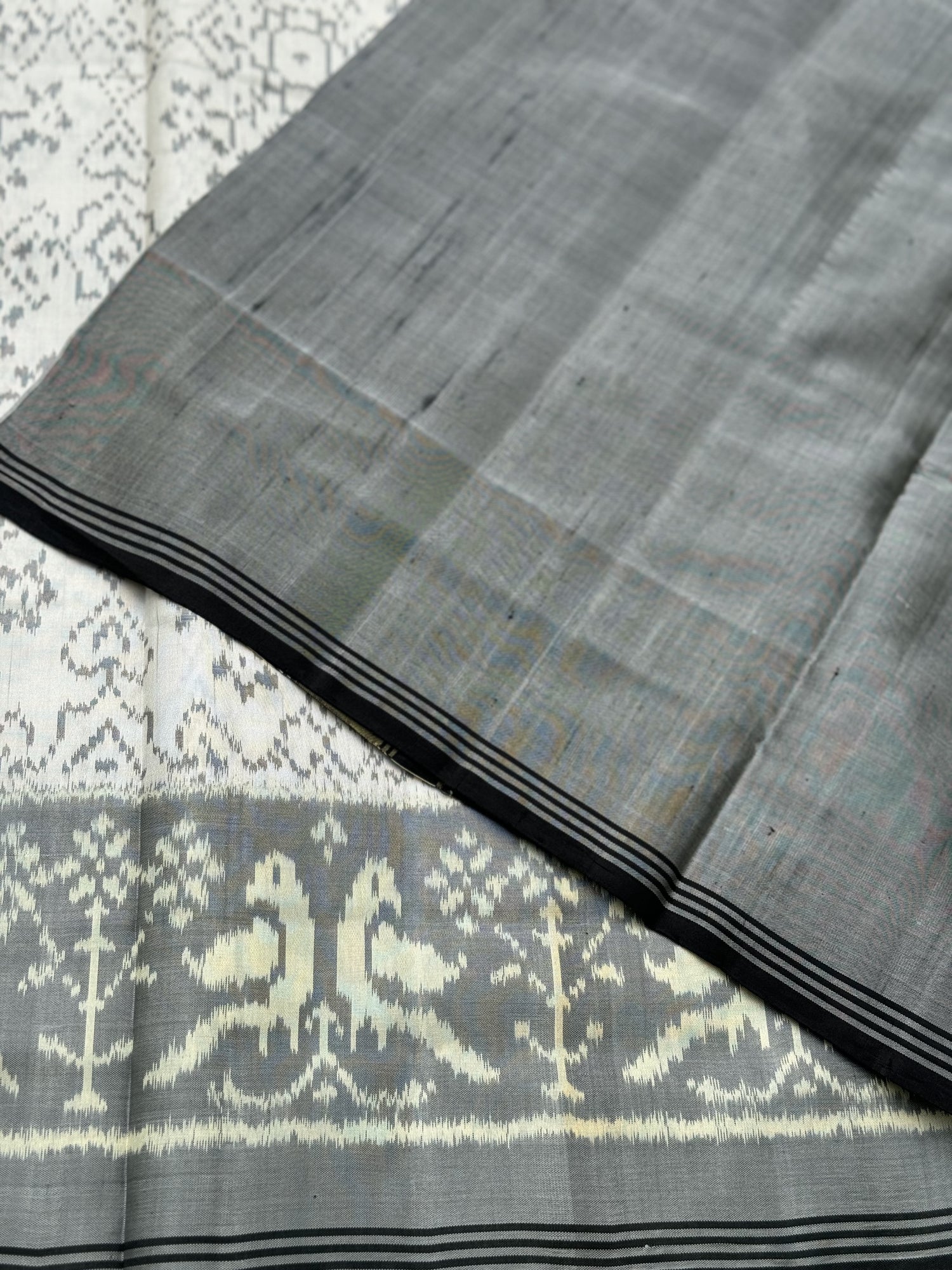 A gorgeous pearl white with grey single ikkat patola silk saree