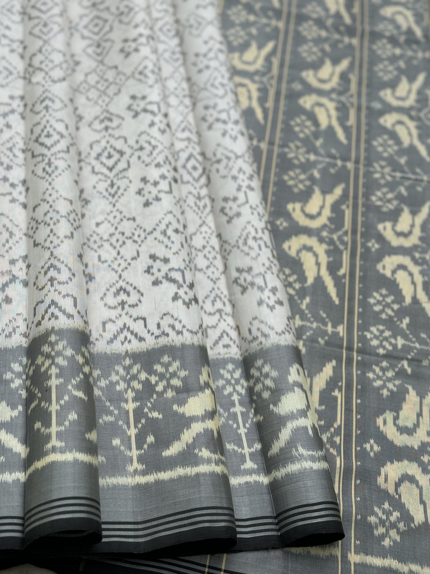 A gorgeous pearl white with grey single ikkat patola silk saree