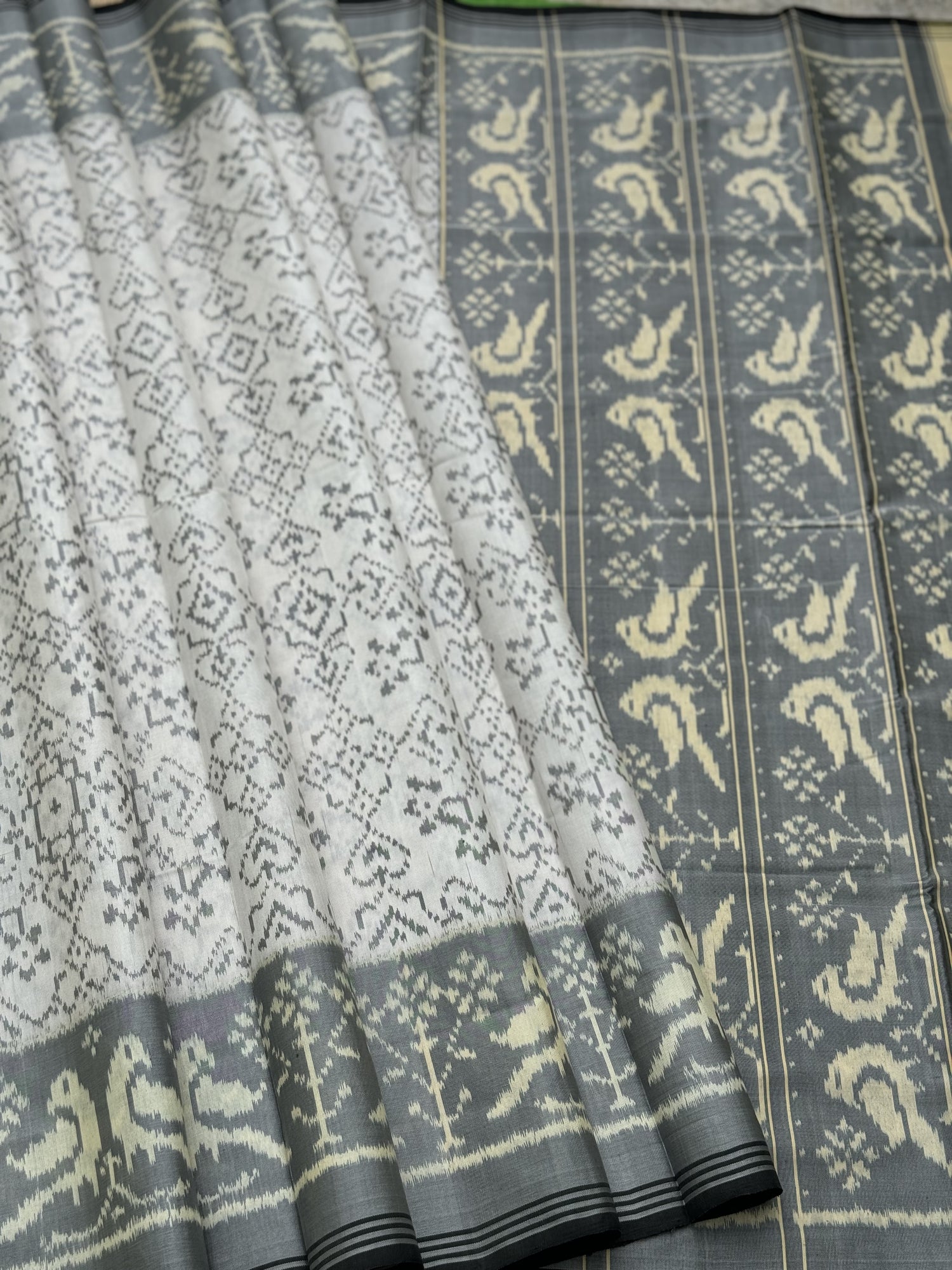 A gorgeous pearl white with grey single ikkat patola silk saree