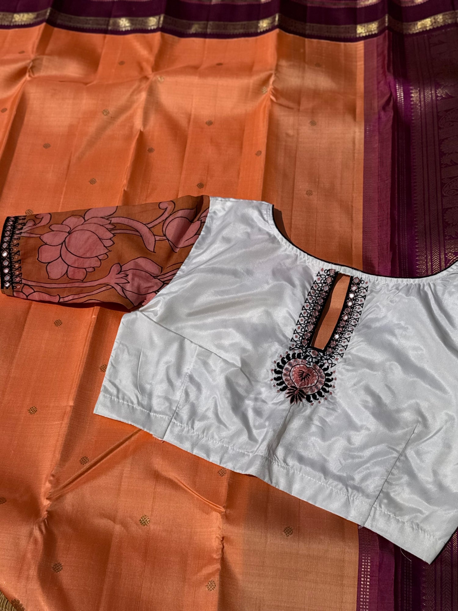The contemporary style on peach orange with ivory white silk penkalamkari blouse