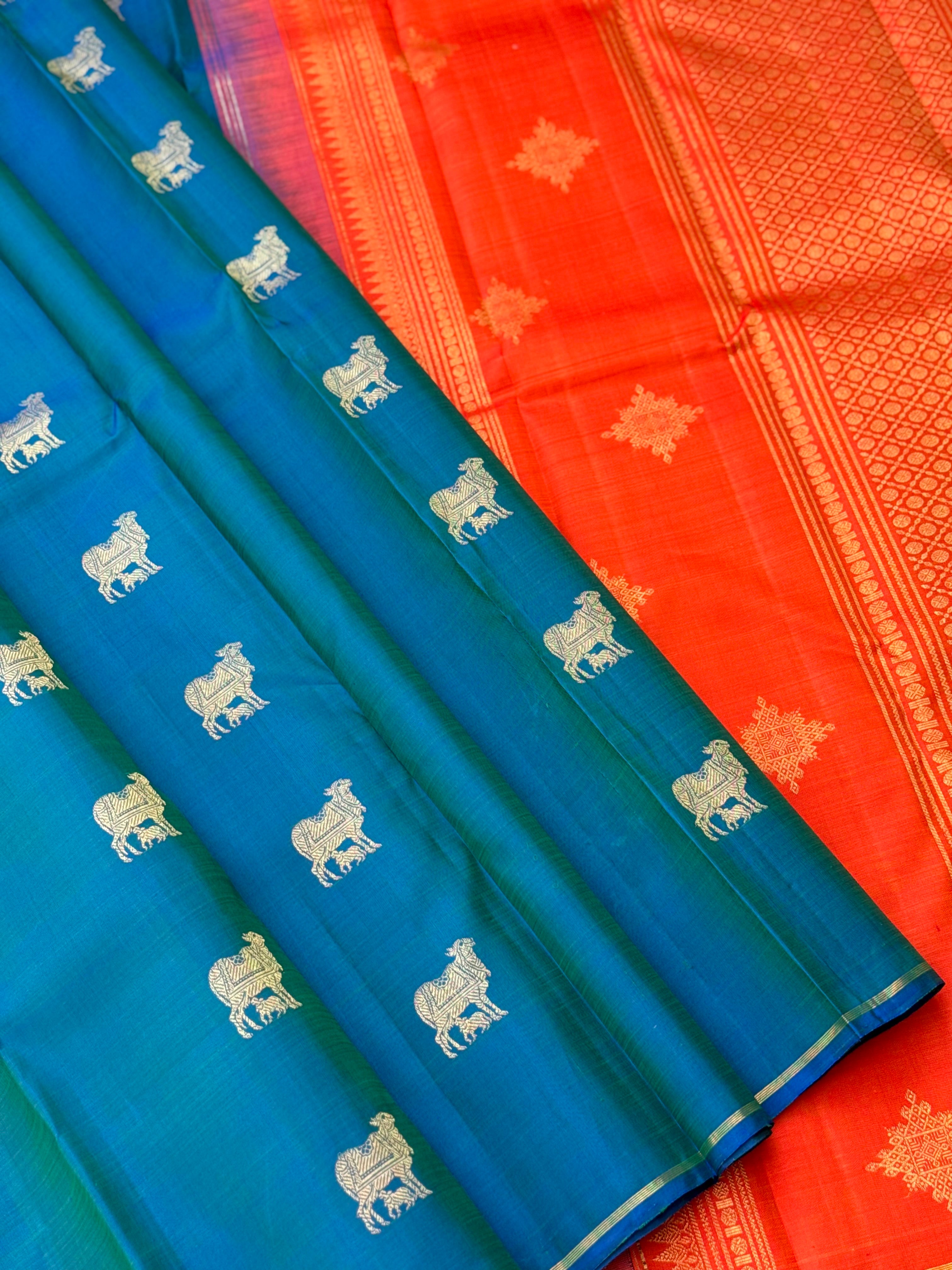 A stunner peacock blue shade with orange borderless kanchivaram silk saree